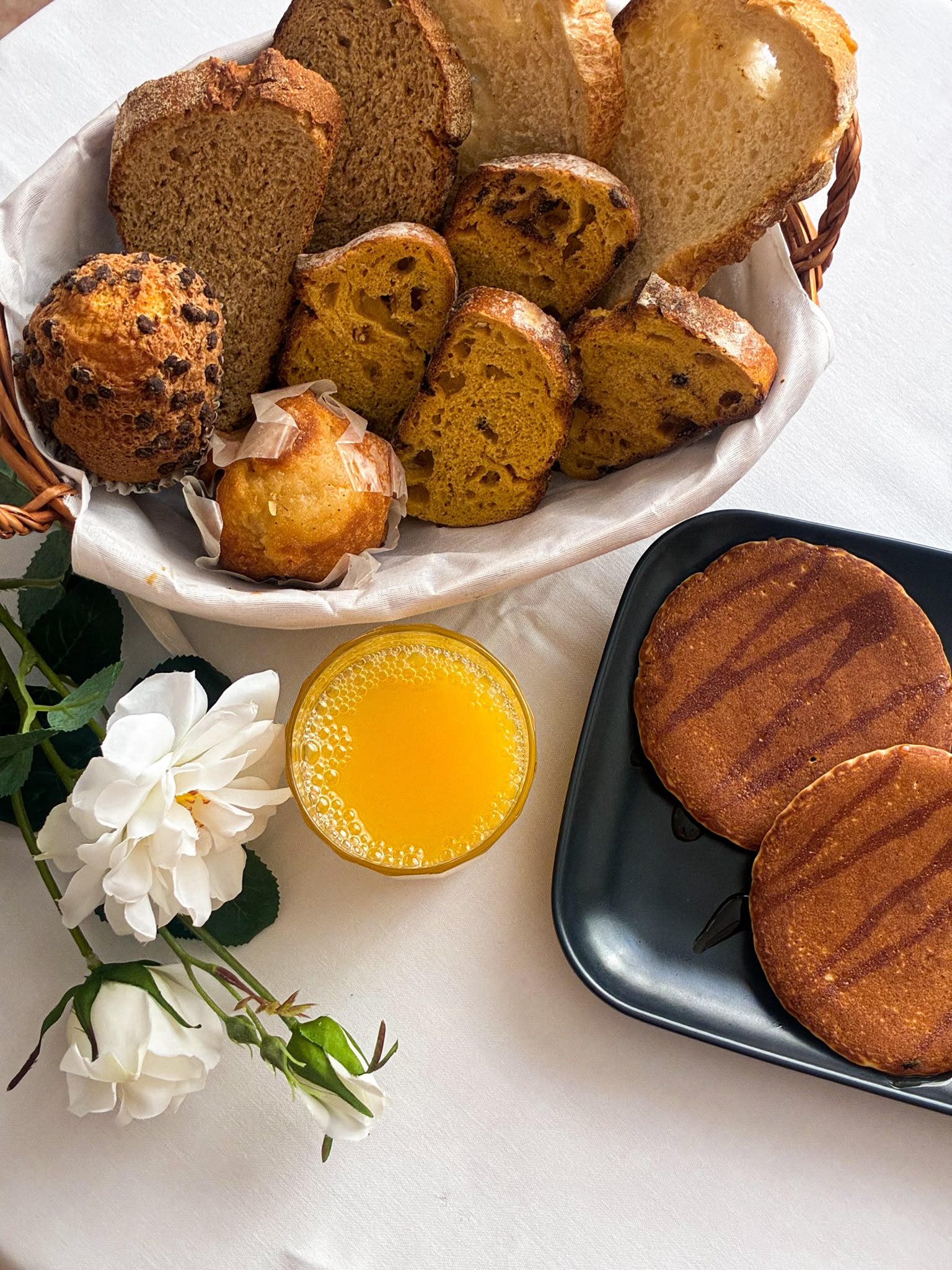 Desayuno con panes, bollería, tortitas y zumo de naranja